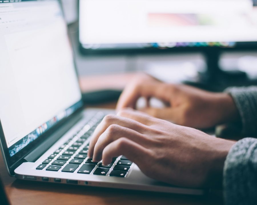 Hands typing at a laptop keyboard